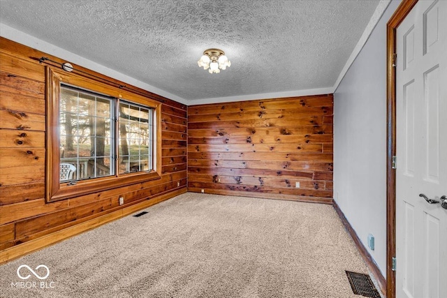 carpeted empty room with wood walls and a textured ceiling