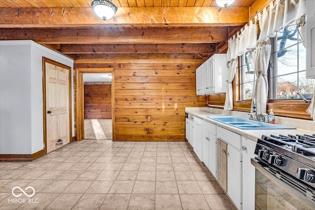 kitchen featuring white cabinets, beam ceiling, wooden walls, and wood ceiling