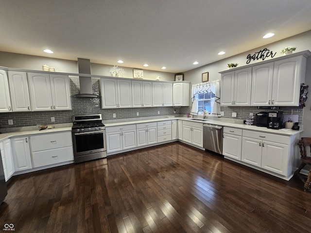 kitchen with appliances with stainless steel finishes, white cabinetry, wall chimney exhaust hood, and sink