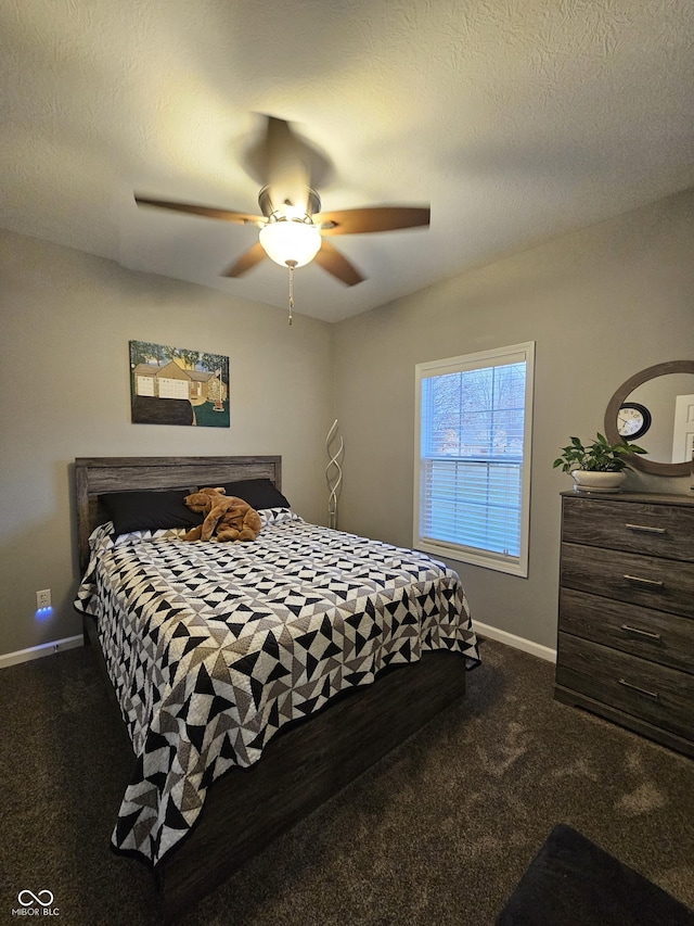 bedroom featuring dark colored carpet, ceiling fan, and a textured ceiling