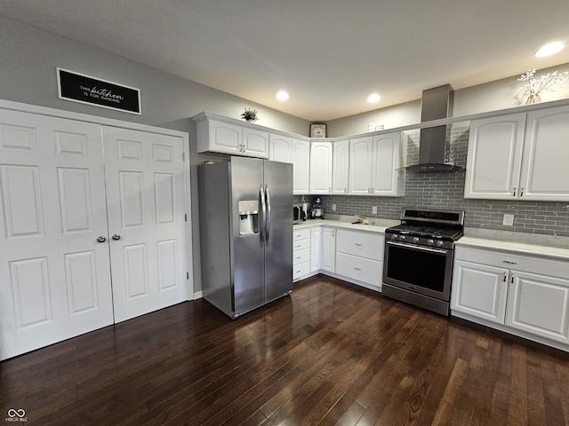 kitchen featuring white cabinets, dark hardwood / wood-style floors, wall chimney range hood, and appliances with stainless steel finishes