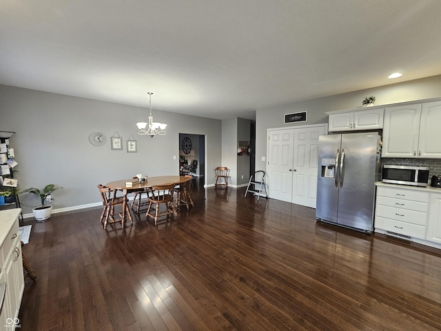 dining space featuring dark wood-type flooring and an inviting chandelier