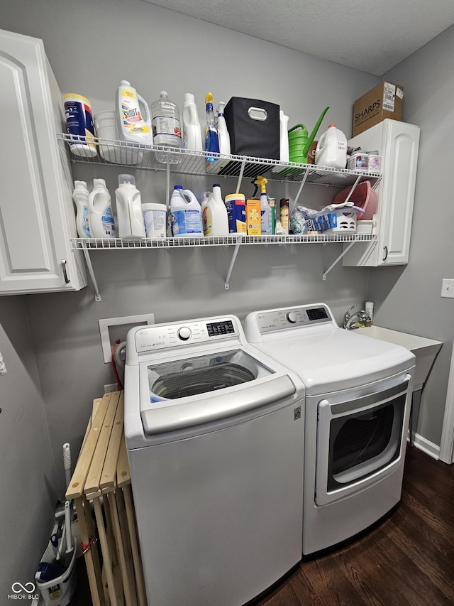 laundry area featuring washer and clothes dryer, cabinets, dark wood-type flooring, and a textured ceiling