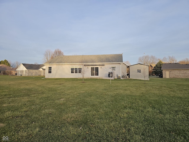 rear view of property featuring a yard and a storage unit