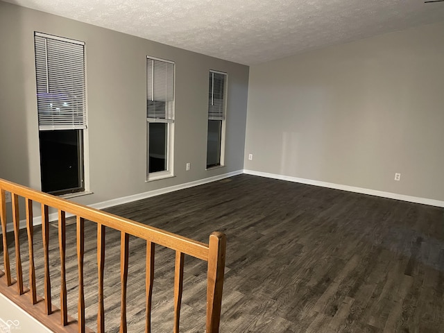 empty room with dark hardwood / wood-style floors and a textured ceiling