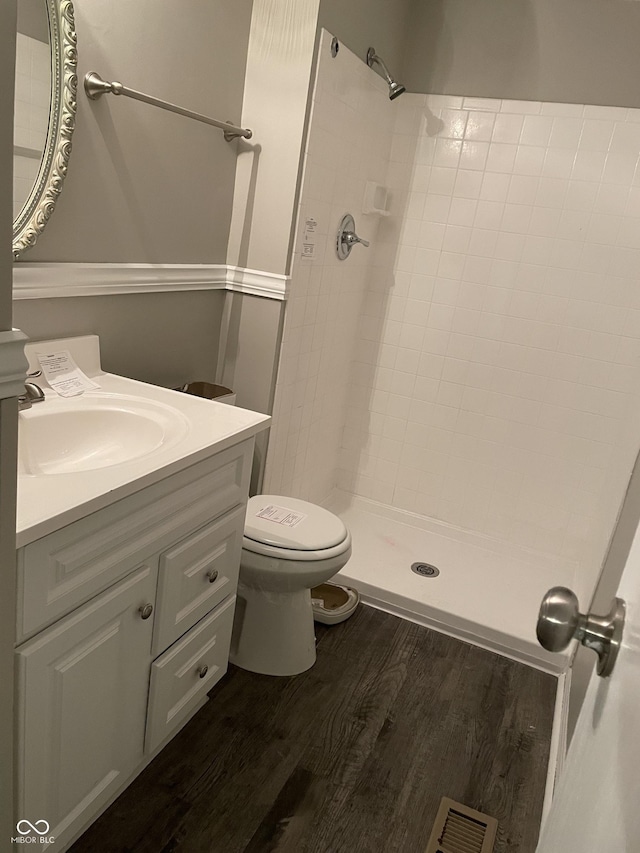 bathroom featuring tiled shower, hardwood / wood-style floors, vanity, and toilet