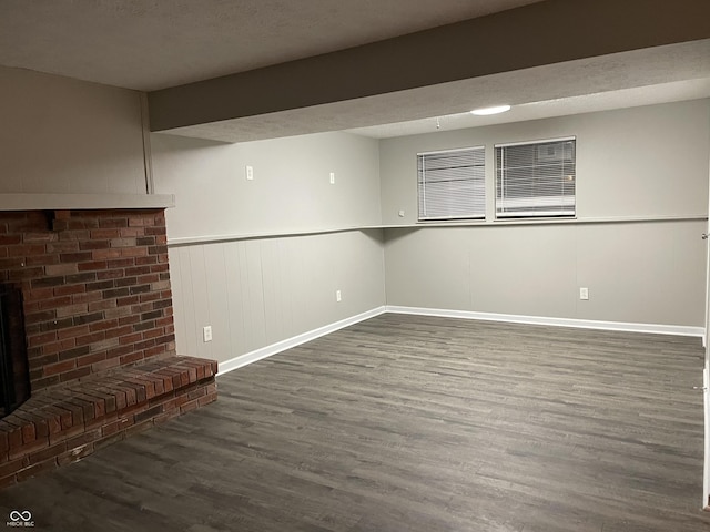 interior space with dark hardwood / wood-style flooring, a textured ceiling, and a brick fireplace