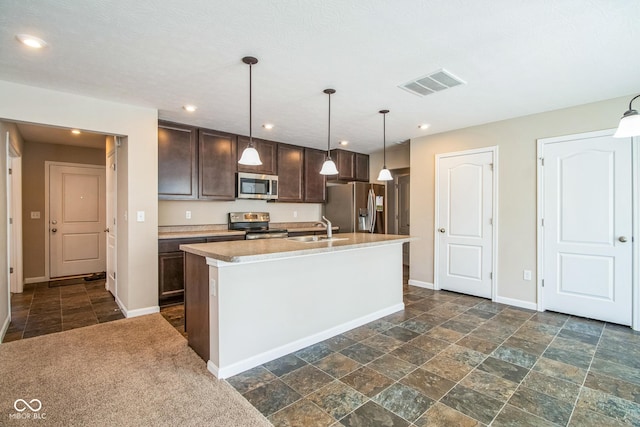 kitchen featuring a kitchen island with sink, hanging light fixtures, sink, dark brown cabinetry, and stainless steel appliances