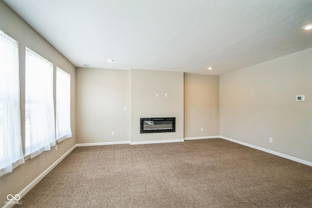 unfurnished living room featuring carpet, a textured ceiling, and a healthy amount of sunlight