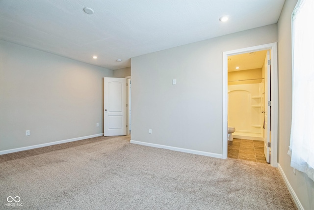 unfurnished bedroom featuring connected bathroom, light colored carpet, and multiple windows