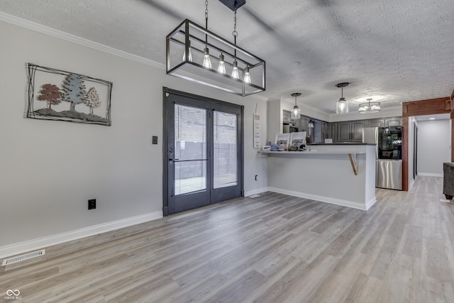 kitchen with kitchen peninsula, stainless steel fridge, crown molding, a textured ceiling, and light wood-type flooring