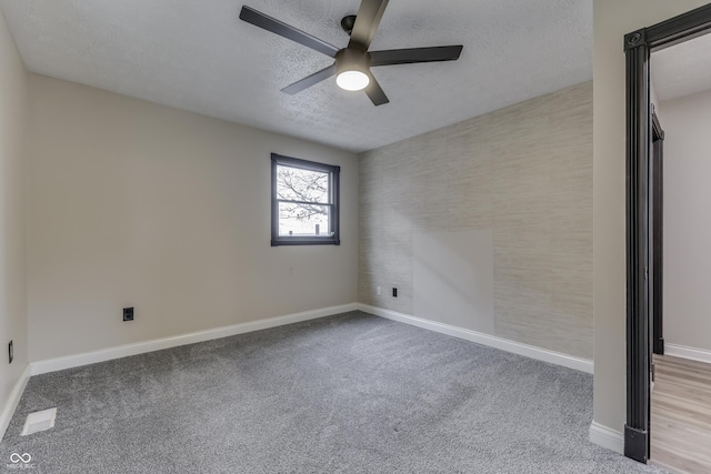 carpeted spare room with ceiling fan and a textured ceiling