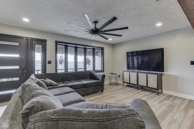 living room with ceiling fan, light hardwood / wood-style floors, and a textured ceiling