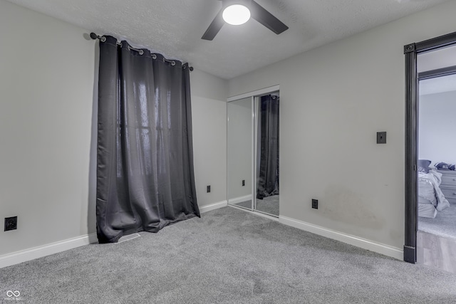 unfurnished bedroom with carpet flooring, a textured ceiling, a closet, and ceiling fan