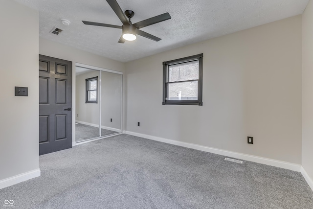 carpeted spare room with ceiling fan and a textured ceiling