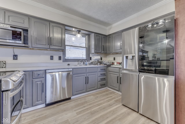 kitchen with light wood-type flooring, gray cabinetry, a textured ceiling, stainless steel appliances, and sink