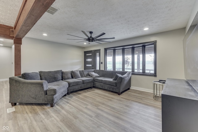 living room featuring beam ceiling, light wood-type flooring, and a textured ceiling