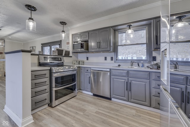 kitchen with gray cabinetry, crown molding, sink, appliances with stainless steel finishes, and light hardwood / wood-style floors