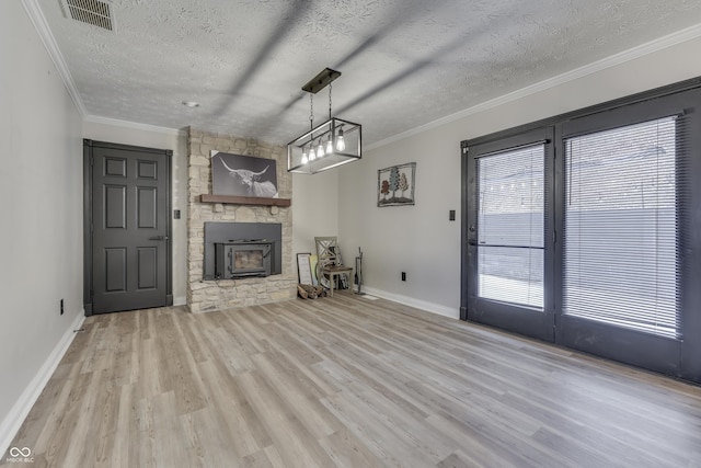 unfurnished living room featuring crown molding, a fireplace, light hardwood / wood-style floors, and a textured ceiling