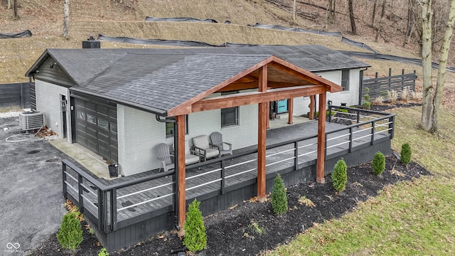 rear view of property featuring central AC and a garage