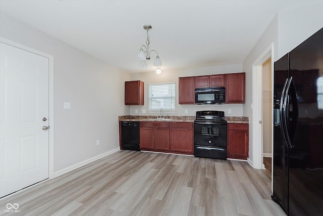 kitchen with black appliances, light hardwood / wood-style floors, sink, and hanging light fixtures