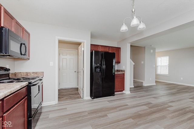 kitchen with pendant lighting, black appliances, a notable chandelier, and light wood-type flooring