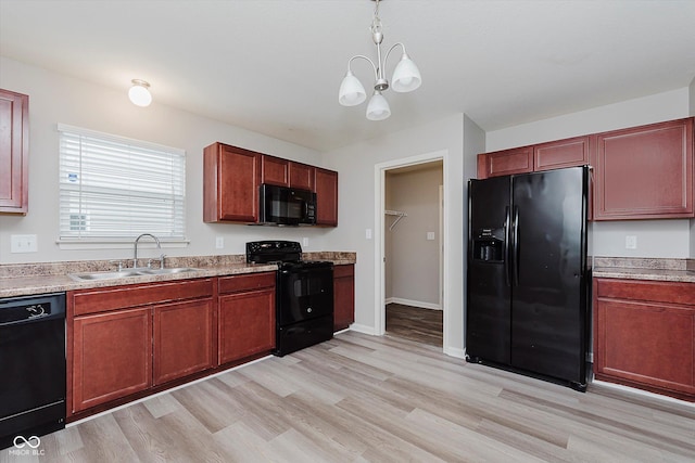 kitchen featuring sink, black appliances, a notable chandelier, and light hardwood / wood-style flooring