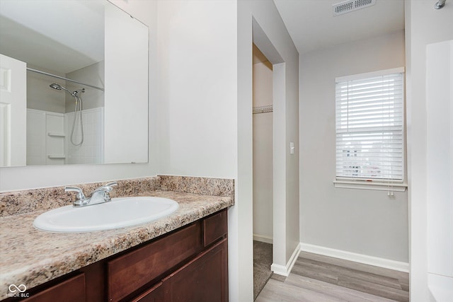 bathroom featuring hardwood / wood-style flooring, vanity, and walk in shower