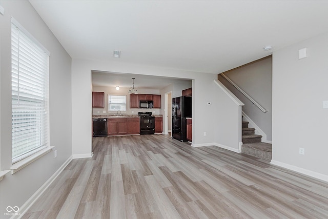 unfurnished living room with light hardwood / wood-style flooring and sink