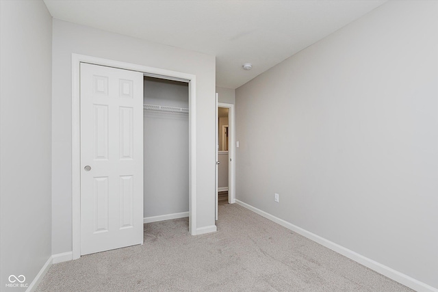 unfurnished bedroom featuring light carpet and a closet