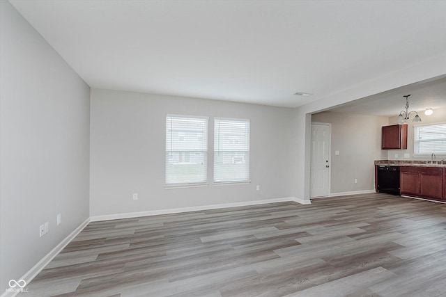 unfurnished living room featuring light hardwood / wood-style flooring, an inviting chandelier, and sink