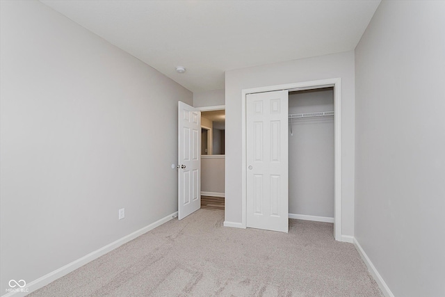 unfurnished bedroom featuring light colored carpet and a closet