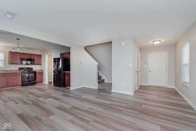 kitchen featuring pendant lighting, black appliances, and light hardwood / wood-style floors