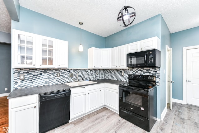 kitchen featuring sink, light hardwood / wood-style flooring, decorative light fixtures, white cabinets, and black appliances