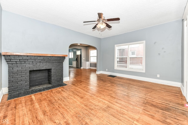 unfurnished living room featuring ceiling fan, a fireplace, a textured ceiling, and hardwood / wood-style flooring