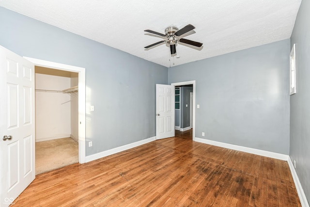 3458 N Kenwood Ave, Indianapolis, IN 46208 - unfurnished bedroom featuring light wood-type flooring, a spacious closet, a textured ceiling, and ceiling fan