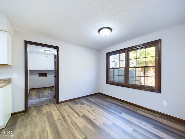 unfurnished room with light hardwood / wood-style floors and a textured ceiling