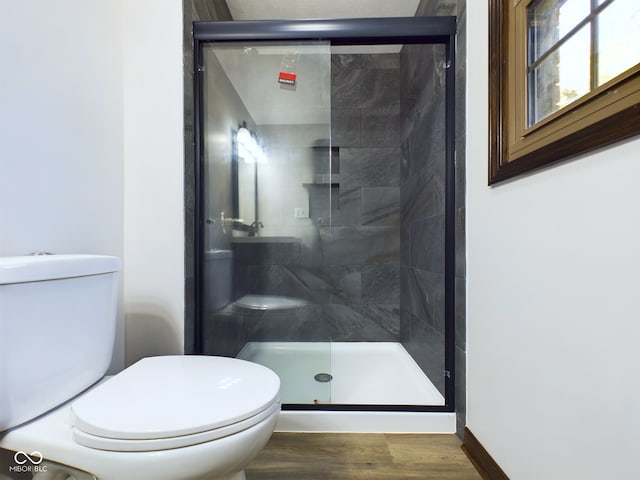 bathroom with hardwood / wood-style floors, a shower with door, and toilet