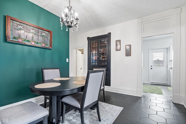 dining room featuring a textured ceiling, dark tile patterned flooring, and a notable chandelier