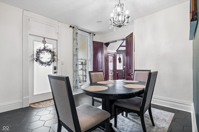 dining area featuring a chandelier, a healthy amount of sunlight, and dark tile patterned flooring