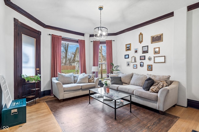 living room with hardwood / wood-style flooring, crown molding, and a notable chandelier