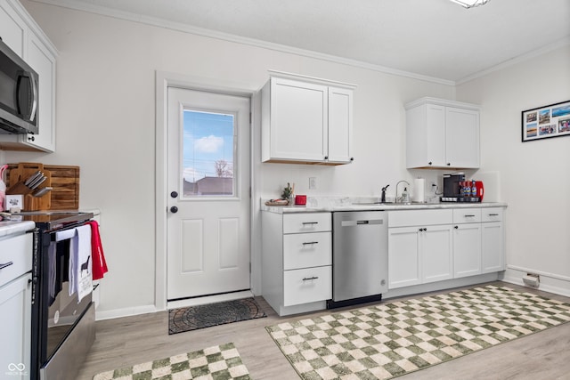 kitchen featuring white cabinets, crown molding, sink, light wood-type flooring, and appliances with stainless steel finishes