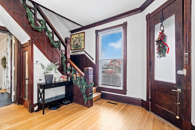 foyer entrance with light hardwood / wood-style floors and ornamental molding