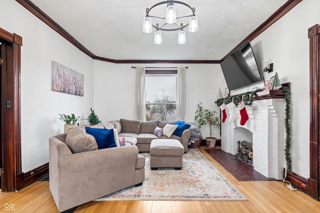 living room with a fireplace, an inviting chandelier, ornamental molding, and light wood-type flooring