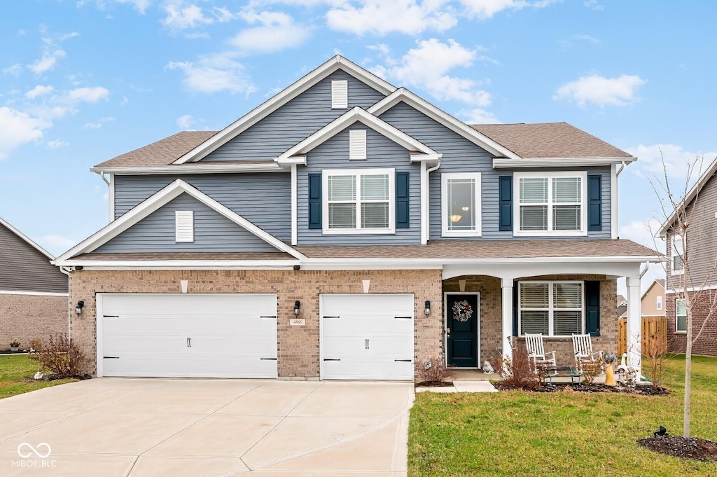 craftsman inspired home with a front yard, a garage, and covered porch