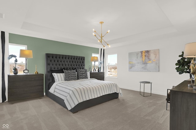 carpeted bedroom with an inviting chandelier and a raised ceiling