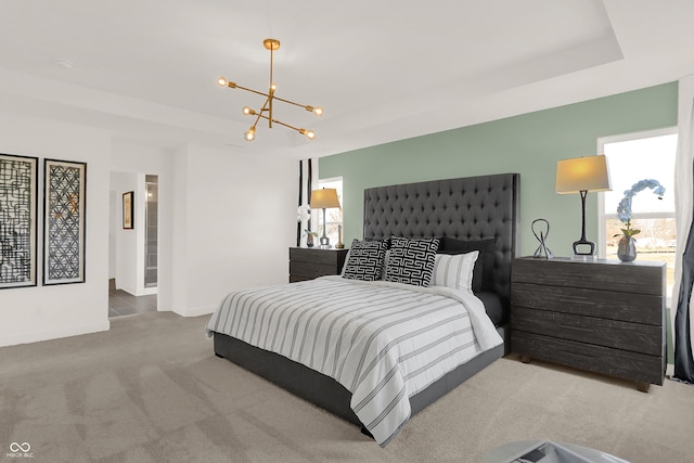 bedroom featuring a notable chandelier, a raised ceiling, and carpet floors