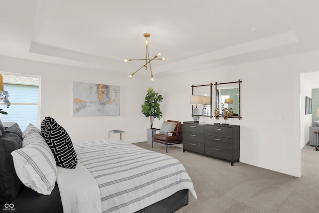 carpeted bedroom with a notable chandelier and a tray ceiling