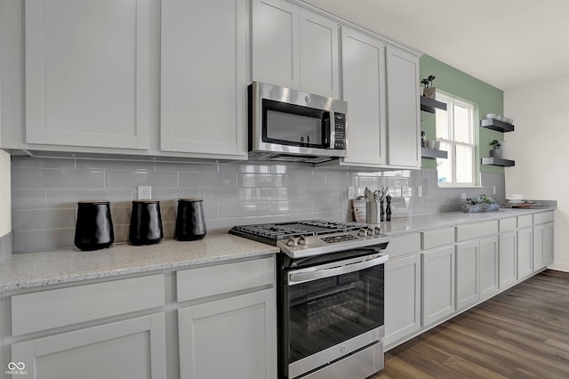 kitchen with light stone countertops, tasteful backsplash, stainless steel appliances, hardwood / wood-style flooring, and white cabinets