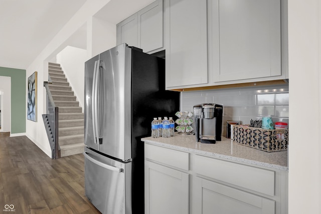 kitchen featuring white cabinets, stainless steel fridge, tasteful backsplash, and light stone counters